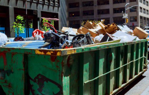 https://www.findadump.com/wp-content/uploads/2021/11/Green-dumpster-filled-with-trash-sitting-on-the-street.jpg